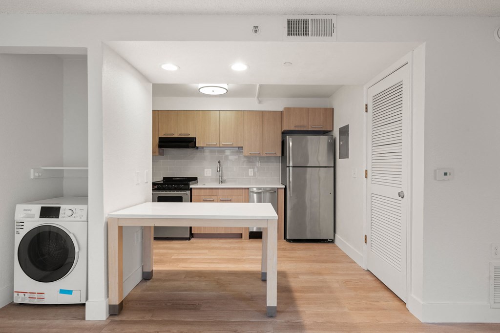 A modern kitchen with a white table and wooden cabinets at AVIA Lofts on Parkway Apartments, Washington, 98662