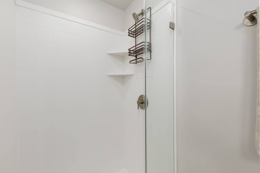 A white bathroom with a white door and a white towel hanging on the wall.