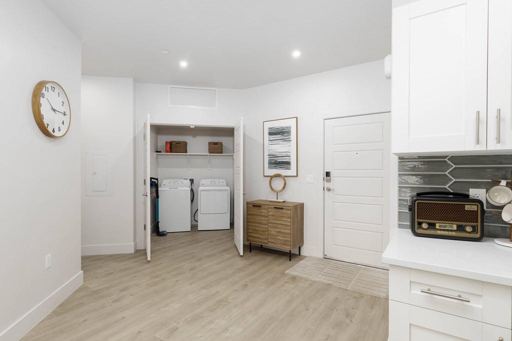 A white laundry room with a clock on the wall and a washer and dryer in the background.