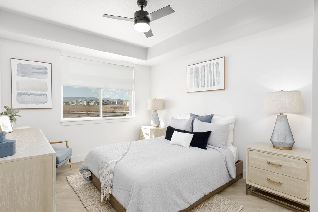 A bedroom with a bed, nightstand, and a ceiling fan.