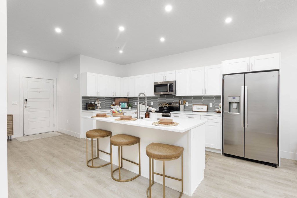 A modern kitchen with a white island and stools.