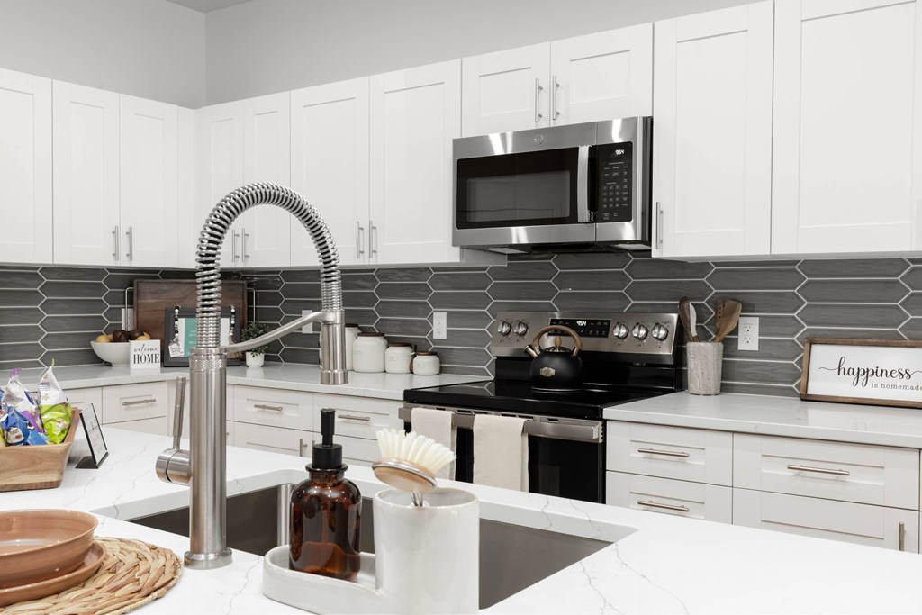 A kitchen with white cabinets and a black stove top oven.