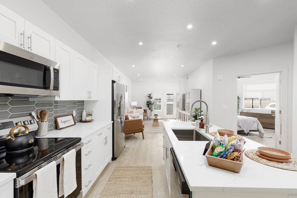 A modern kitchen with white cabinets and a black stove top.
