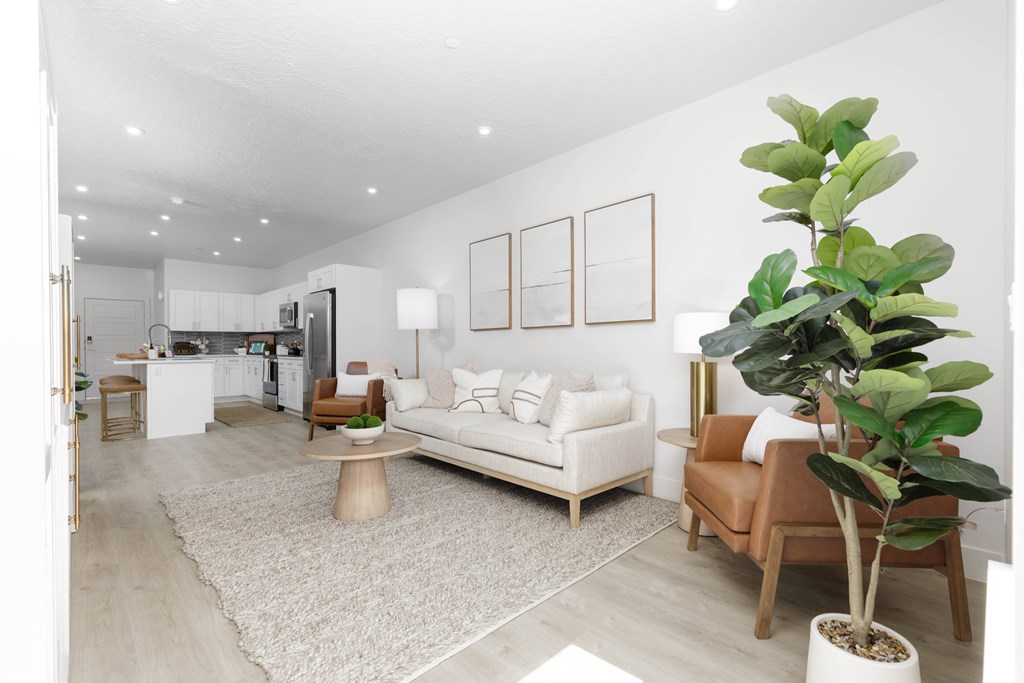 A living room with a white couch, a wooden coffee table, and a large plant.