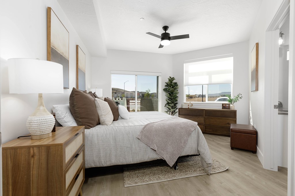 A bedroom with a bed, nightstand, and a ceiling fan.
