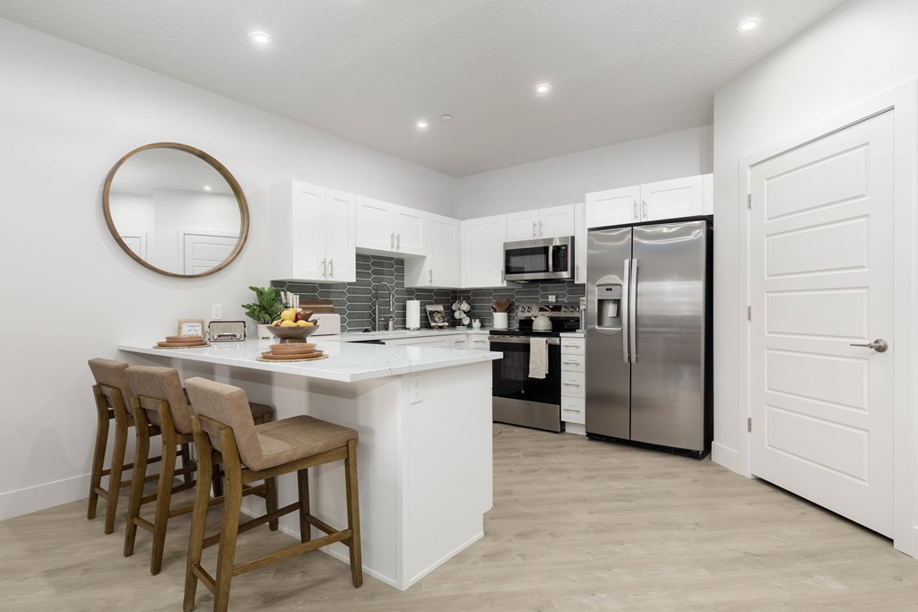 A kitchen with a white island and stainless steel appliances. at The Vue At Desert Color, St. George