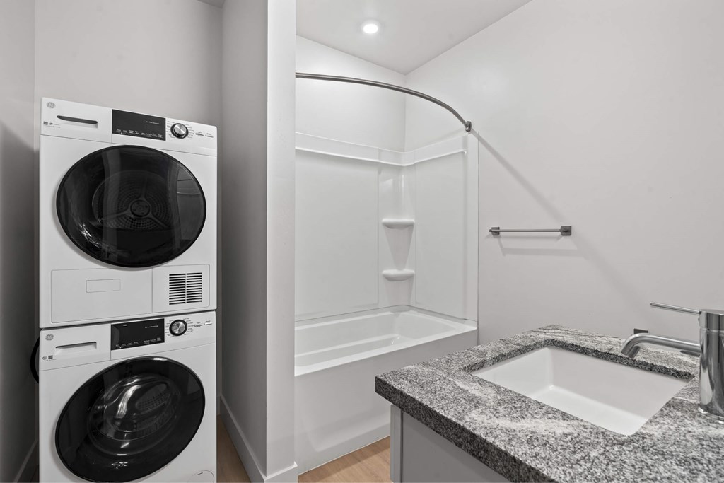 A modern laundry room with a washer and dryer stacked on top of each other. at Brickside Heights, Utah
