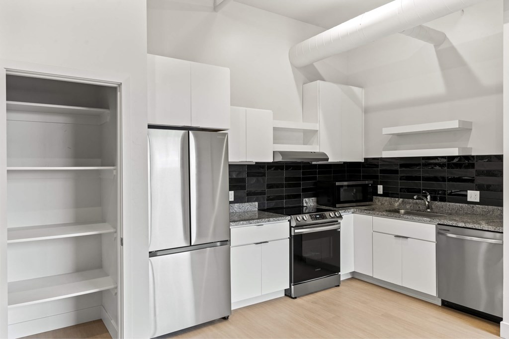 A modern kitchen with stainless steel appliances and white cabinetry. at Brickside Heights, Utah, 84106