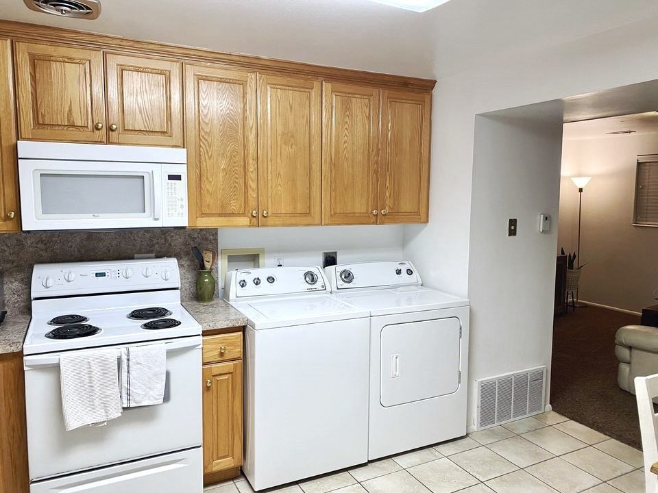 A kitchen with white appliances and wooden cabinets.
