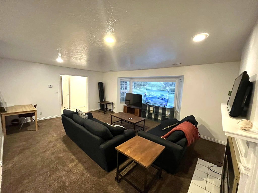 A living room with a black couch and a television on the wall.