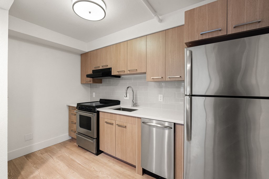 A kitchen with a stainless steel refrigerator, oven, and sink at AVIA Lofts on Parkway Apartments, Washington