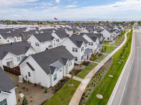 A row of white houses with black roofs are lined up along a street. at Alante Homes at Spring Run, Caldwell
