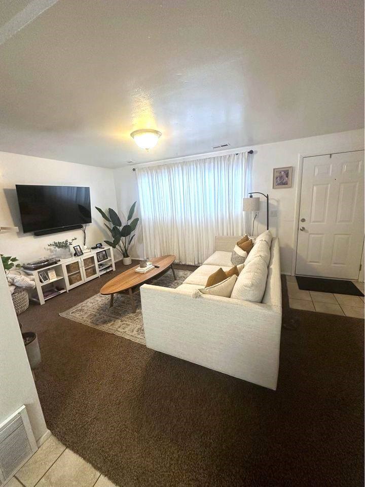 A living room with a white couch and a flat screen TV.