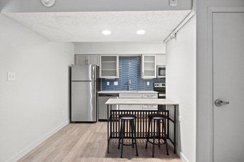a kitchen with a island and stools and a stainless steel refrigerator at AVIA Lofts on Liberty Ridge Apartments, Jacksonville, FL