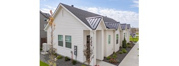 A white house with a grey roof and a grey gravel area in front.