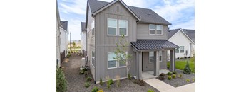 A grey house with a black roof and a gravel driveway. at Alante Homes at Spring Run, Caldwell, 83607