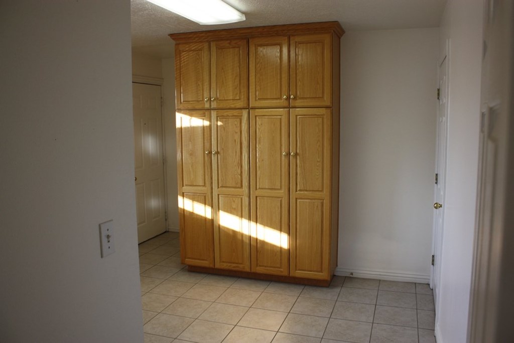 A wooden cabinet with four doors is in a room with white walls.