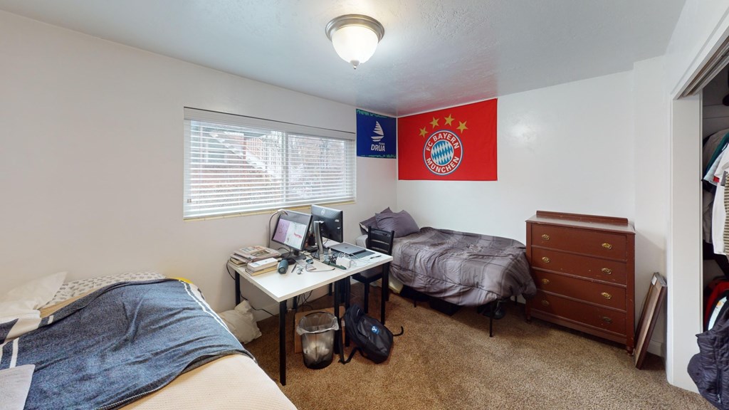 A room with a bed, desk, and a Bayern Munich flag.