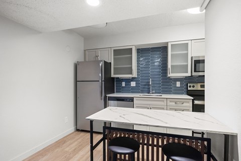 a kitchen with a white island and a stainless steel refrigerator at AVIA Lofts on Liberty Ridge Apartments, Florida