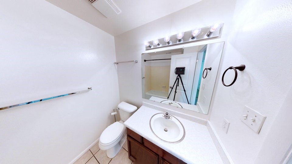 A white bathroom with a toilet, sink, and mirror.
