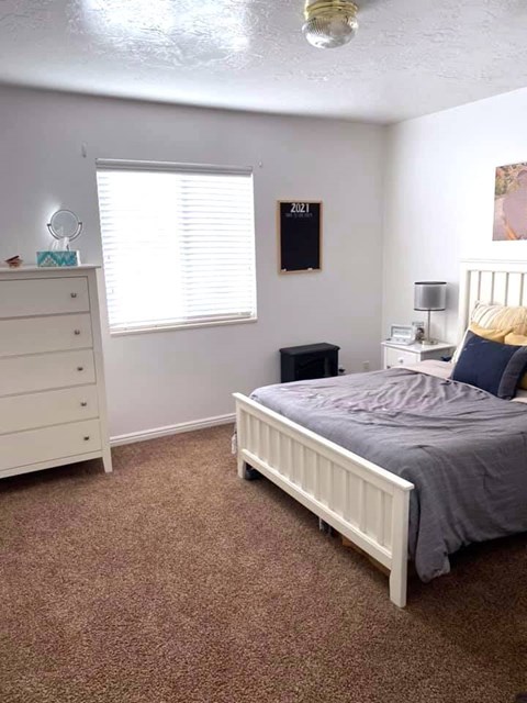 A bedroom with a bed, dresser, and window.