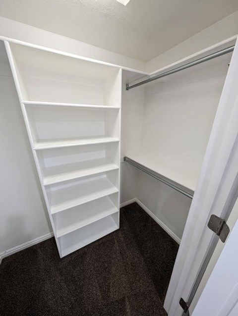A white shelving unit in a room with a white door.