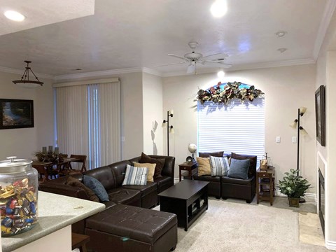 A living room with a brown couch and a glass jar filled with colorful beads on the coffee table.
