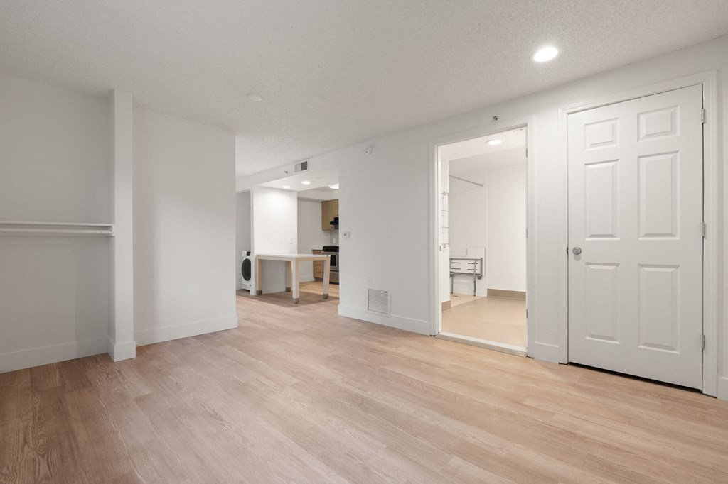 A room with white walls and wooden flooring with a table and chairs in the background at AVIA Lofts on Parkway Apartments, Vancouver