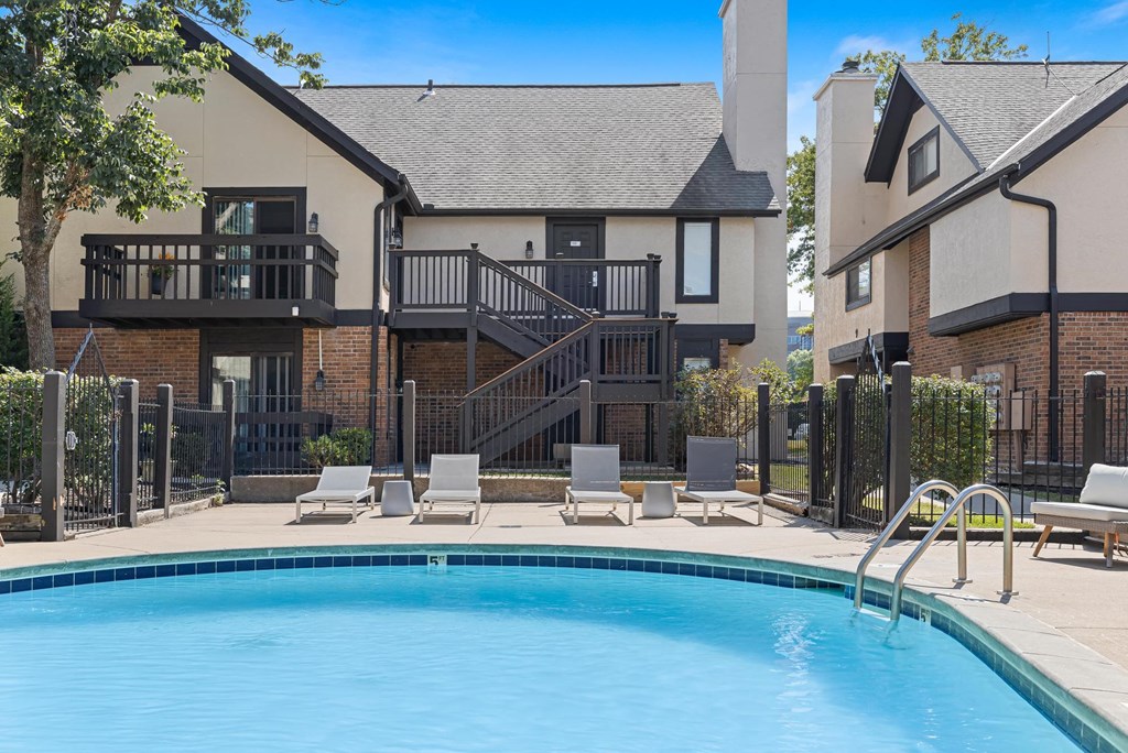 a swimming pool with chairs and a house in the background