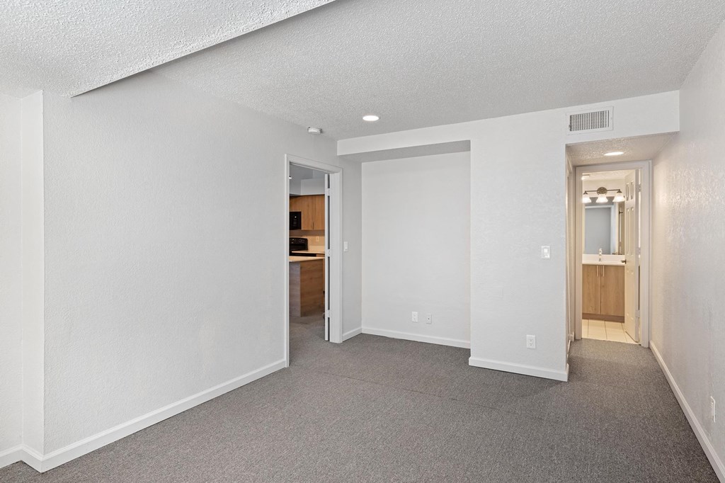 the living room and kitchen of an apartment with white walls