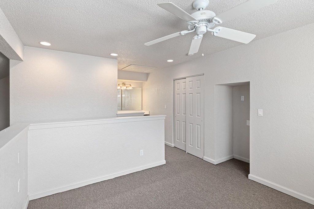 an empty room with a ceiling fan and a door to a bathroom