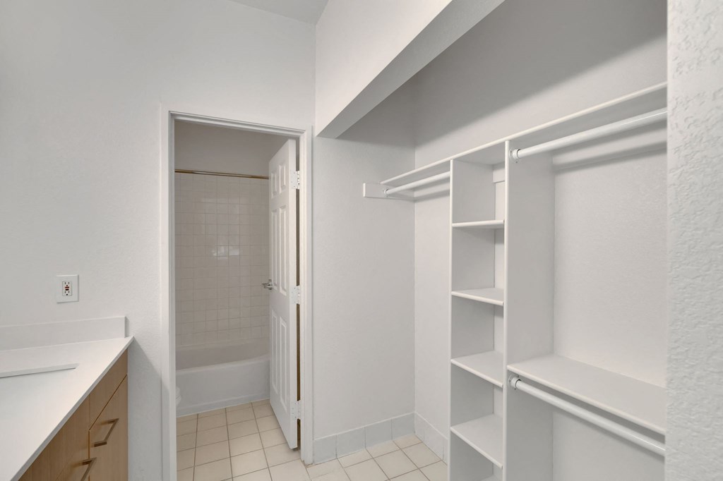 a walk in closet with white shelving and a door to a bathroom