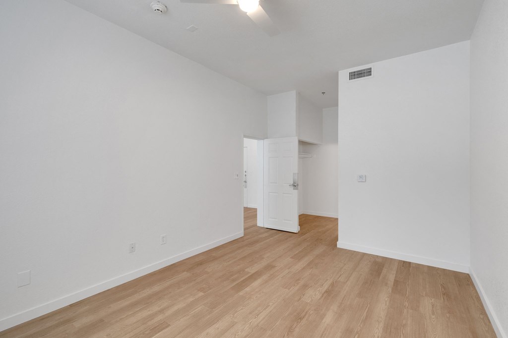 the living room and dining room of an apartment with white walls and wood floors