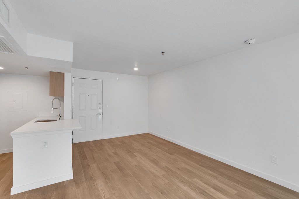a living room and kitchen with white walls and wood floors
