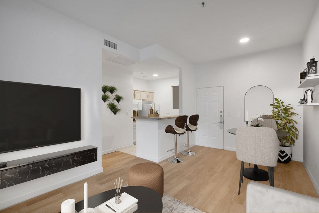 a living room with a large tv and a kitchen in the background