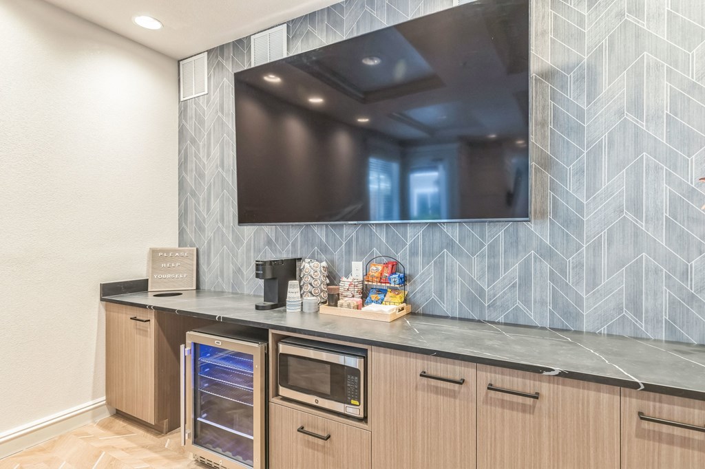 a kitchen with a large tv on the wall and a counter with a dishwasher
