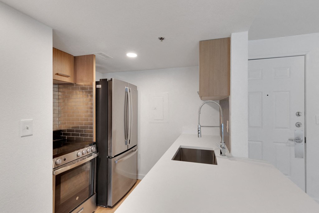 a kitchen with a white counter top and a stainless steel refrigerator