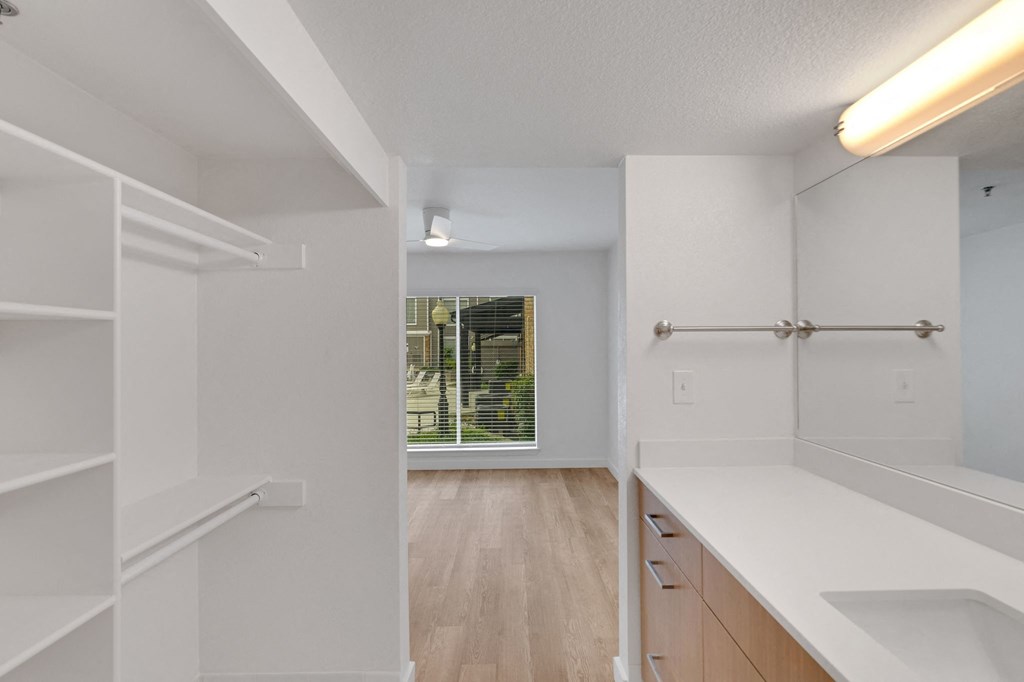the living room and kitchen of an apartment with white cabinets and a window