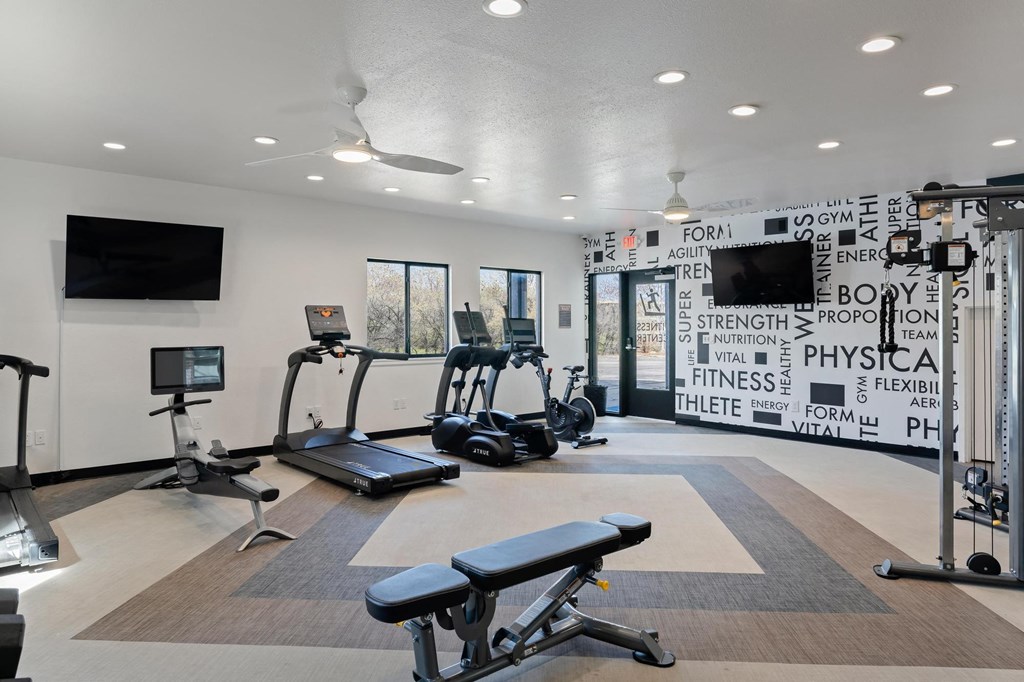 a gym with treadmills and other exercise equipment and flat screen televisions