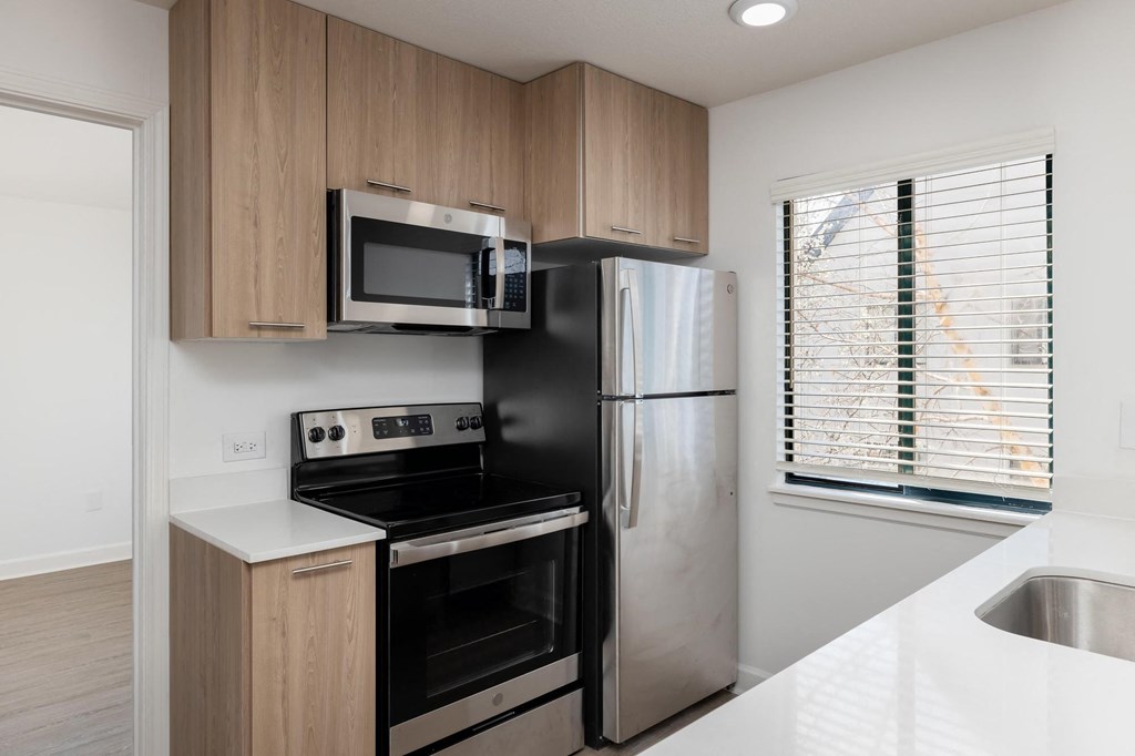 a small kitchen with white countertops and wooden cabinets