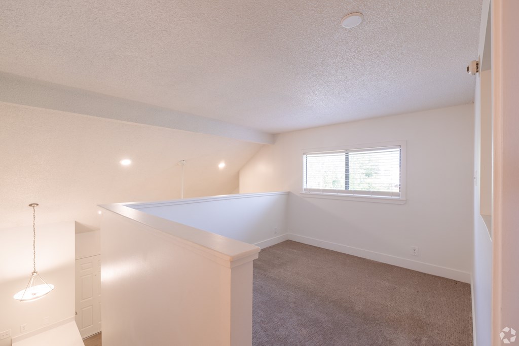 the living room and dining room in a renovated home with white walls and carpet