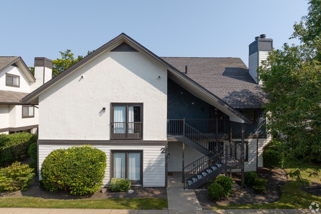 an exterior view of a white house with a balcony and a staircase