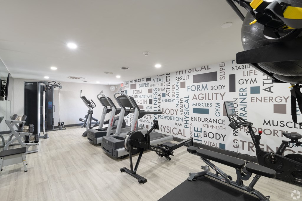 a gym with various machines and a wall with words on it