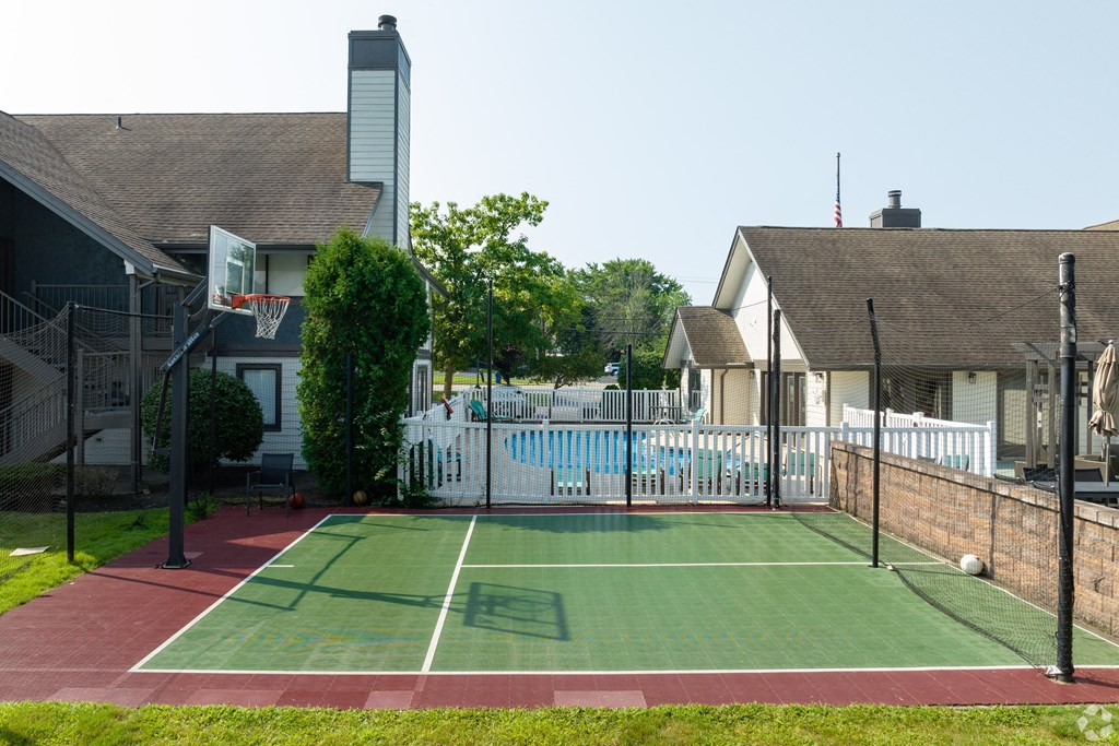 a tennis court in front of a house with a pool