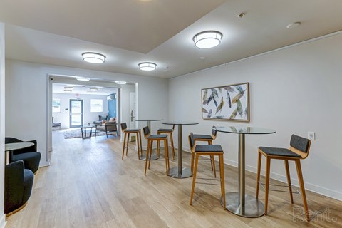a communal area with tables and chairs in a living room