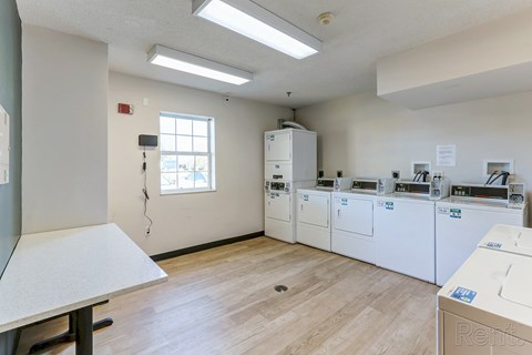 a kitchen with washes and dryers in it and a window and a table