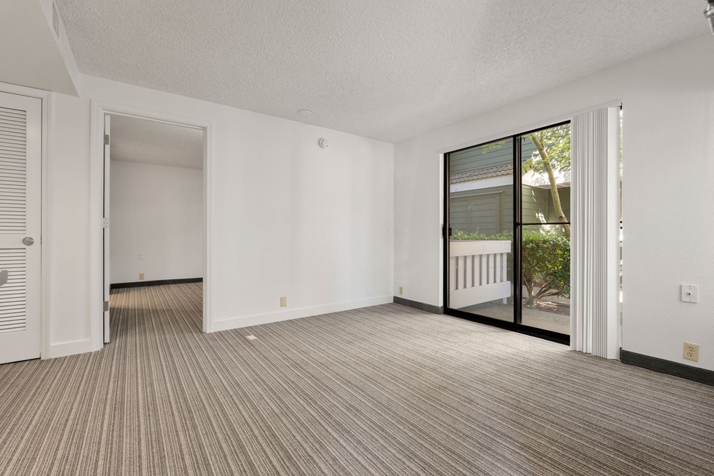 an empty living room with a sliding glass door to a balcony at AVIA Lofts on Parkway Apartments, Washington