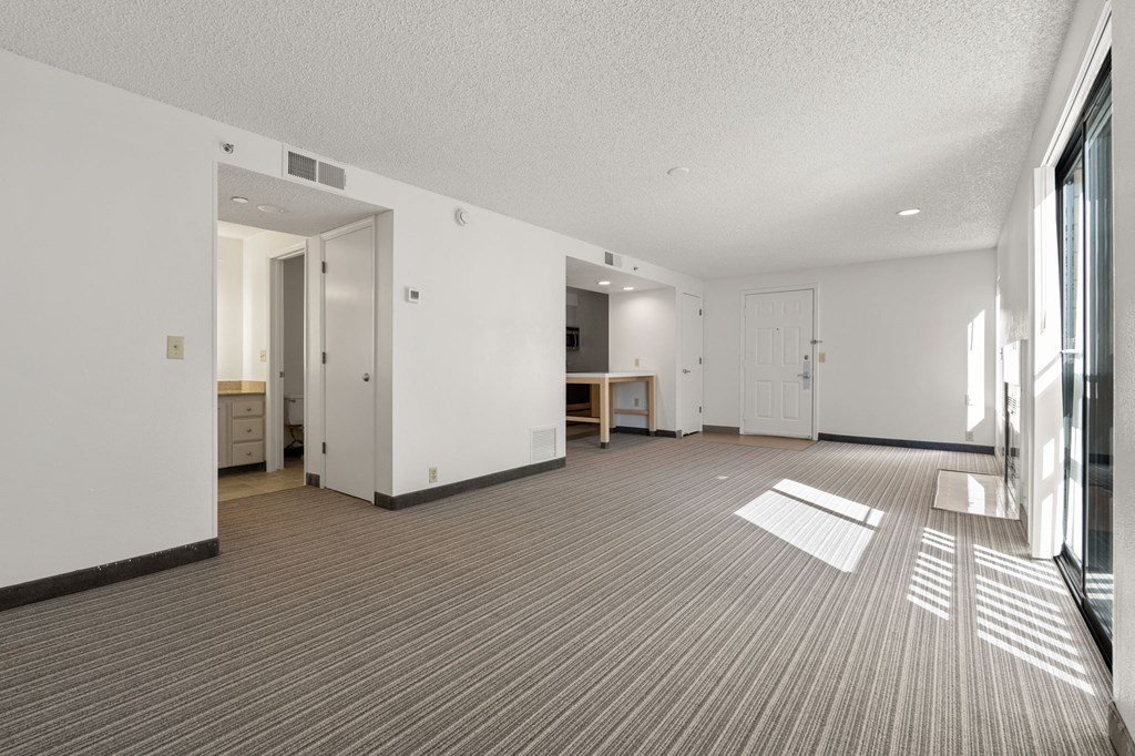 the living room and dining room of an apartment with white walls and a striped carpet at AVIA Lofts on Parkway Apartments, Vancouver