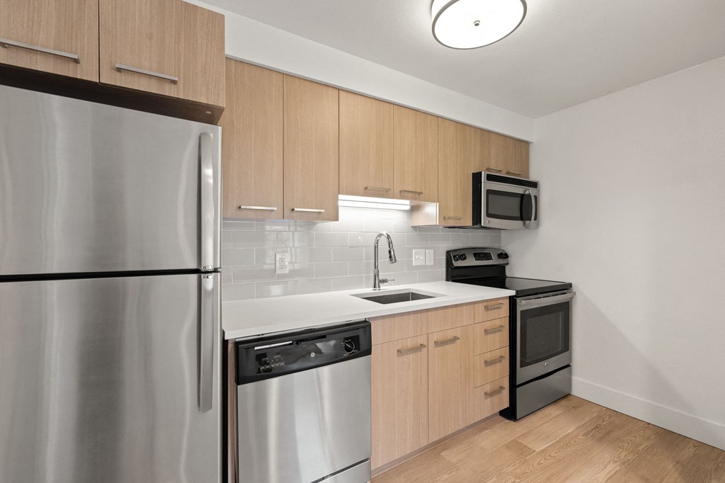 an empty kitchen with stainless steel appliances and wooden cabinets at AVIA Lofts on Parkway Apartments, Vancouver, WA, 98662