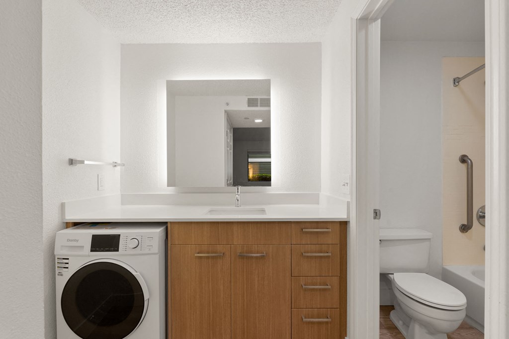 a bathroom with a washing machine and a sink and a mirror at AVIA Lofts on Parkway Apartments, Washington, 98662